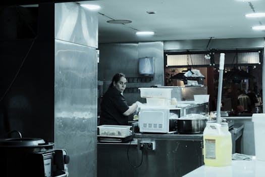 a chef using a microwave in a professional kitchen